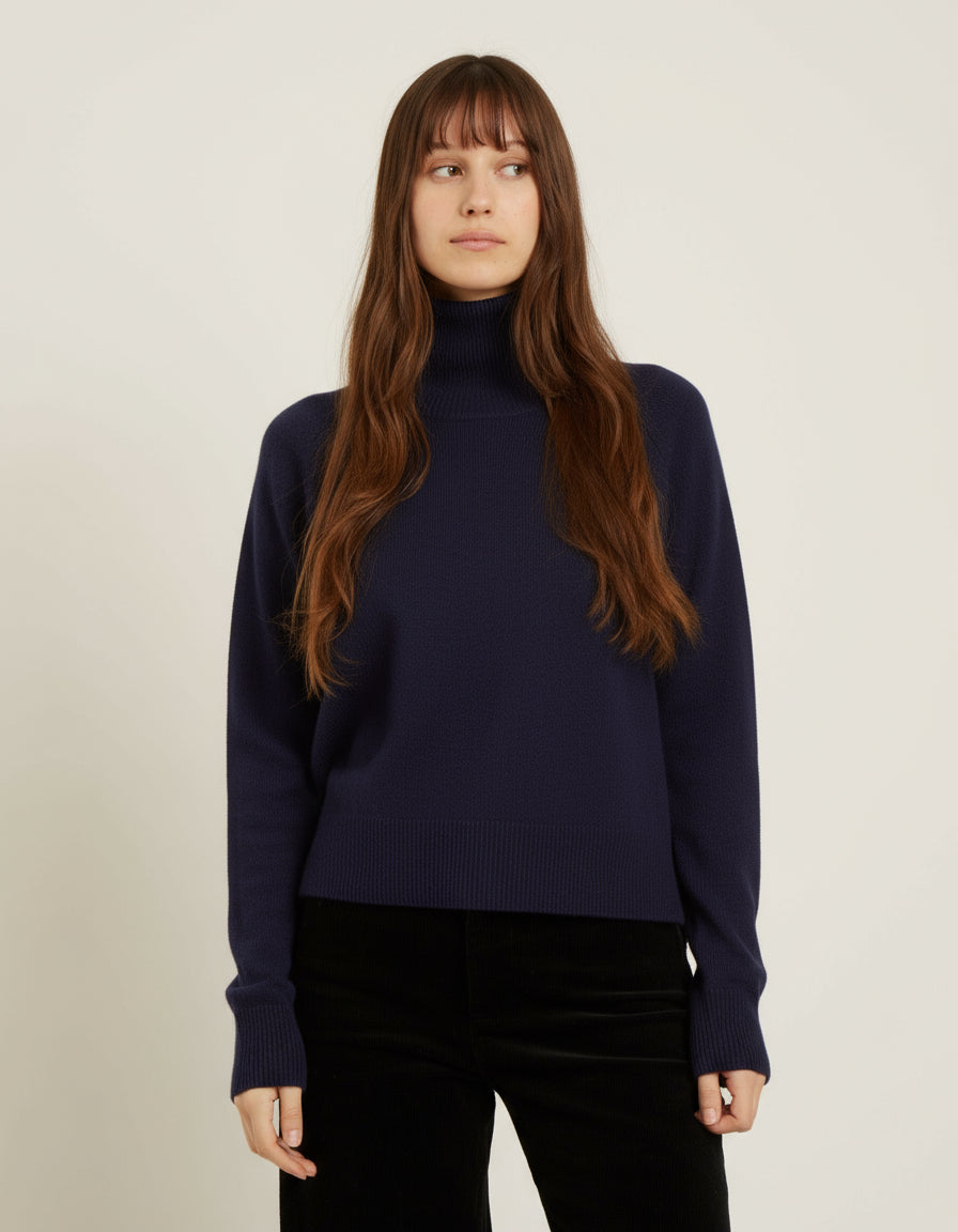 Woman wearing an olive green turtleneck sweater against a plain background