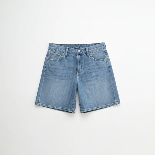 Woman wearing a green off-shoulder top and denim shorts on a white background
